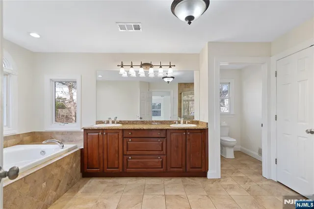 a spacious bathroom with a granite countertop sink and a bathtub