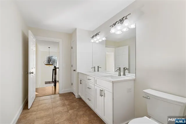 a spacious bathroom with a double vanity sink toilet and a mirror