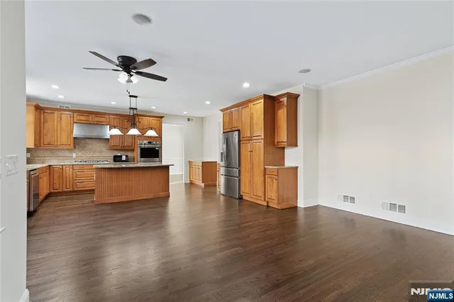 a view of kitchen with stainless steel appliances wooden floor and chair