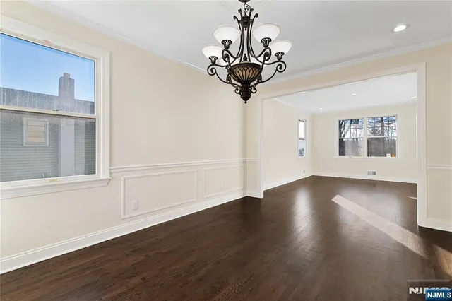 a view of a room with wooden floor chandelier and windows