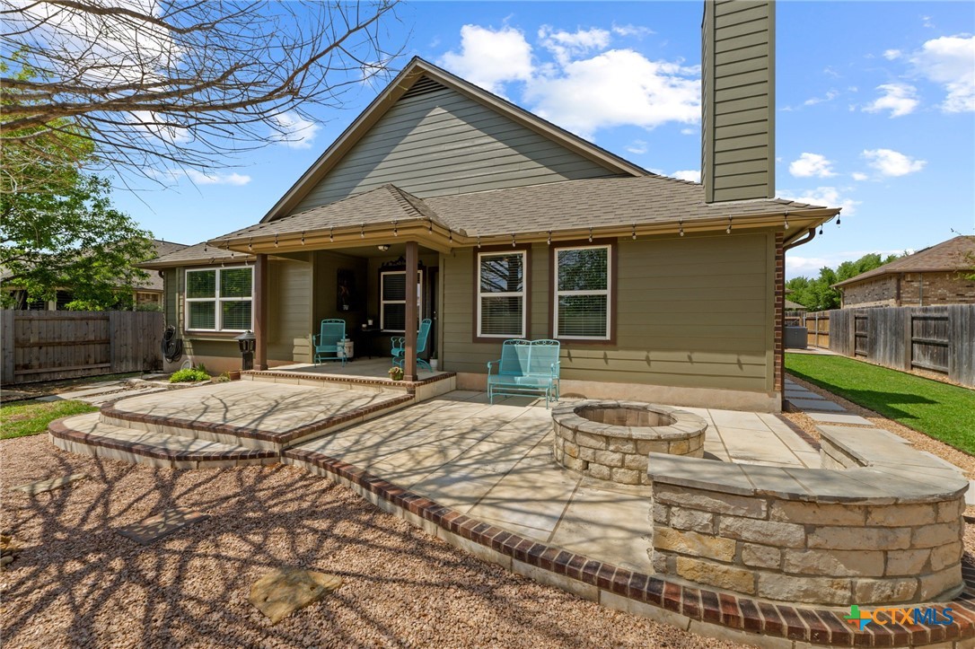 20525 Jackies Ranch Boulevard Pflugerville, TX 78660 - Photo 27 of 30 Back of house featuring a fenced backyard, a patio area, a shingled roof, a fire pit, and a chimney