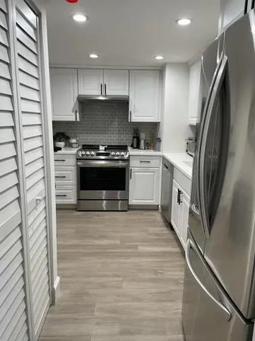 a large kitchen with stainless steel appliances granite countertop a stove a sink and a refrigerator