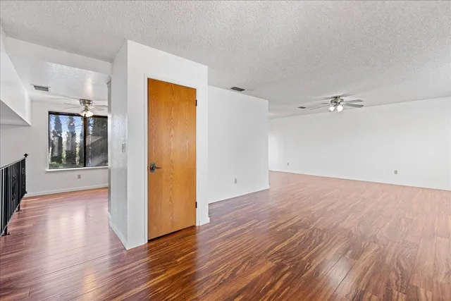 an empty room with wooden floor and a kitchen