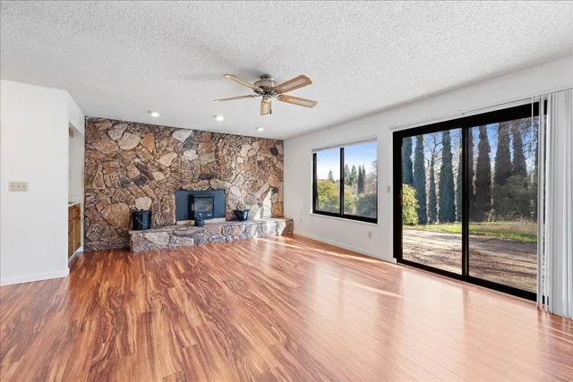 a view of an empty room with wooden floor fireplace and a window