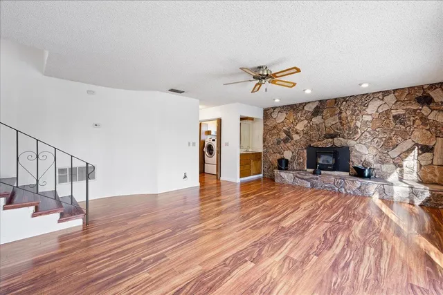 a view of an empty room with wooden floor and a fireplace