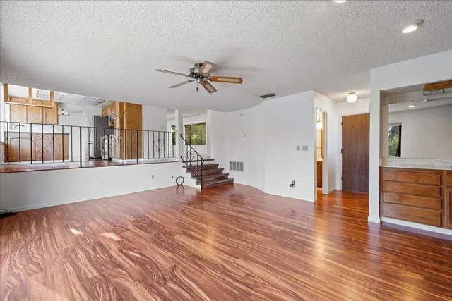 a view of an empty room with a window and wooden floor