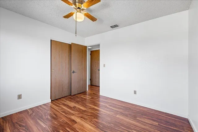 a view of a room with wooden floor and a ceiling fan