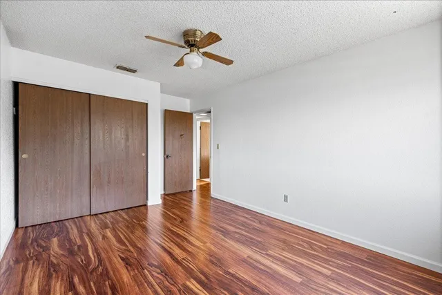 a view of empty room with wooden floor and fan