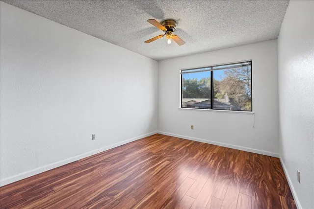 a view of empty room with wooden floor and fan