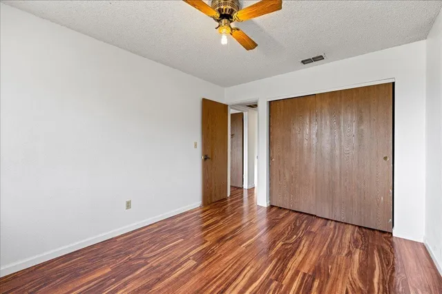 an empty room with wooden floor and a ceiling fan