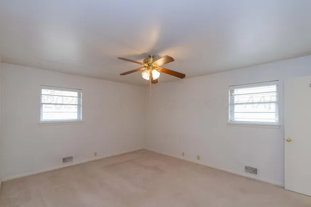 an empty room with windows and chandelier fan
