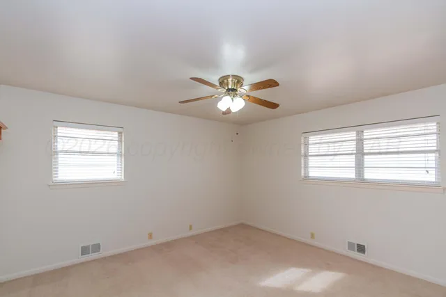 an empty room with a window and a fan