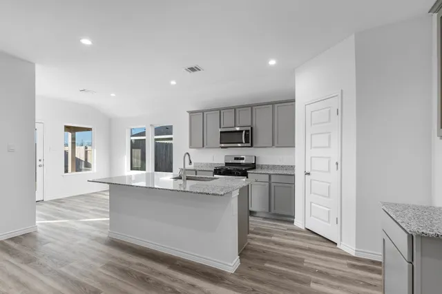 a large kitchen with cabinets wooden floor and stainless steel appliances