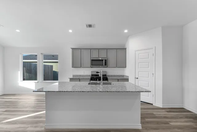 a large kitchen with stainless steel appliances granite countertop a granite counter tops and a stove