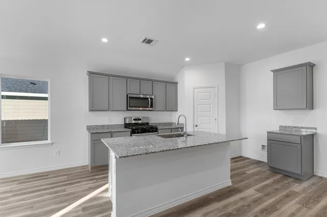 a kitchen with stainless steel appliances granite countertop a sink stove and refrigerator