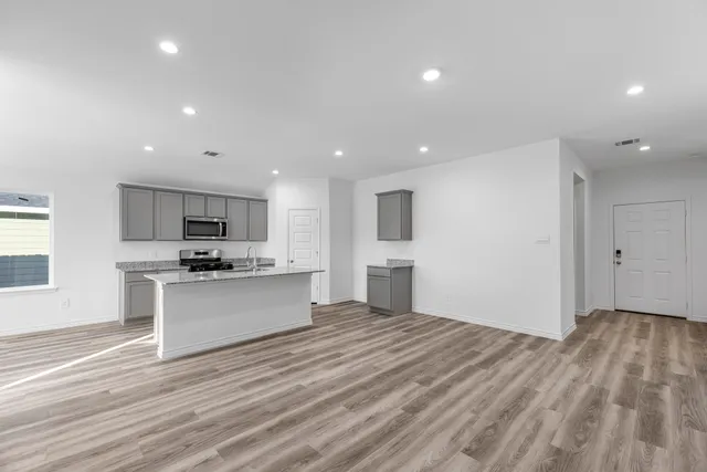 a large kitchen with stainless steel appliances a large counter top a stove and a refrigerator