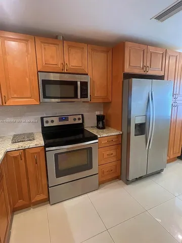 a kitchen with granite countertop a refrigerator stove and microwave