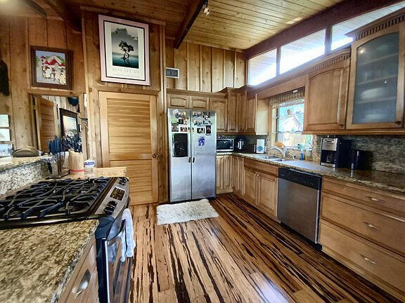 136 Palermo Drive Islamorada, FL 33036 - Photo 15 of 38 a kitchen with stainless steel appliances granite countertop a stove top oven a sink dishwasher a refrigerator and cabinets with wooden floor