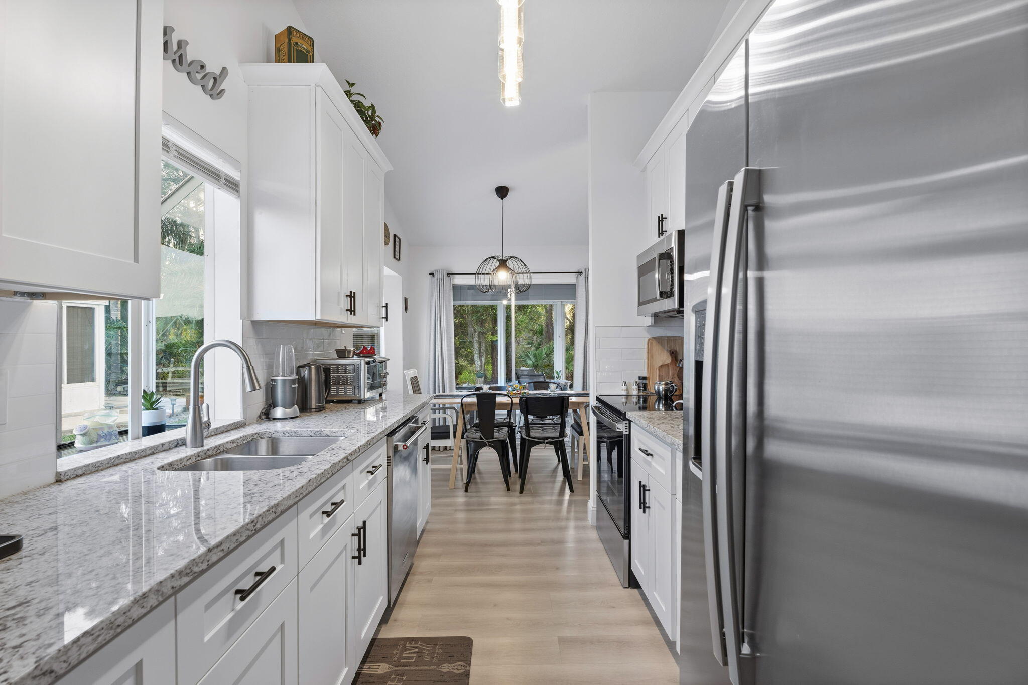 3822 Southeast Canvasback Place Stuart, FL 34997 - Photo 15 of 38 a kitchen with stainless steel appliances granite countertop a refrigerator a sink dishwasher a stove and a dining table with wooden floor