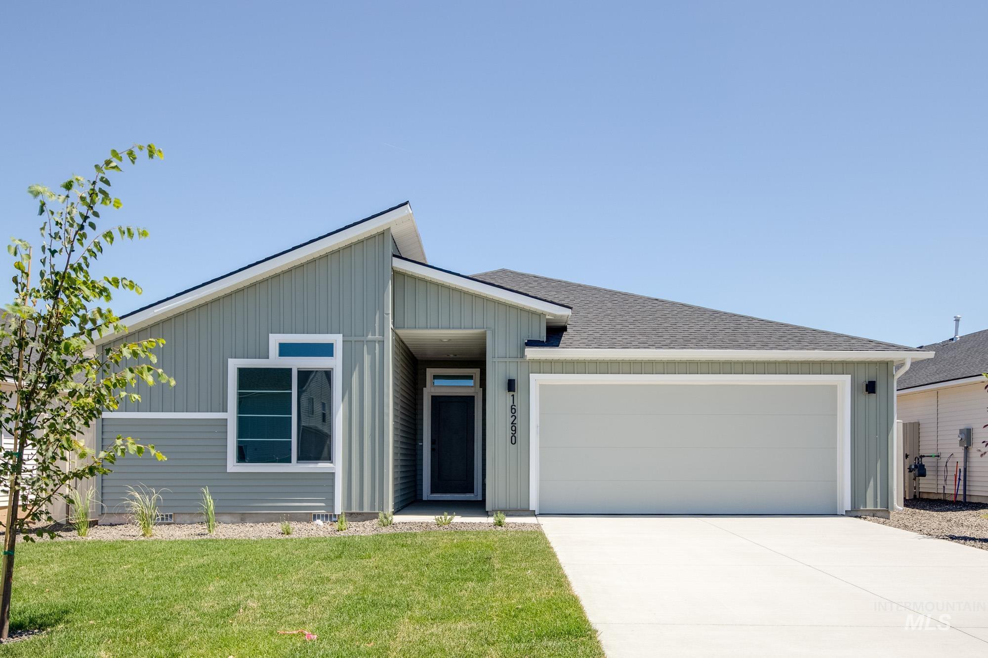 View of front facade with an attached garage, a front yard, and driveway