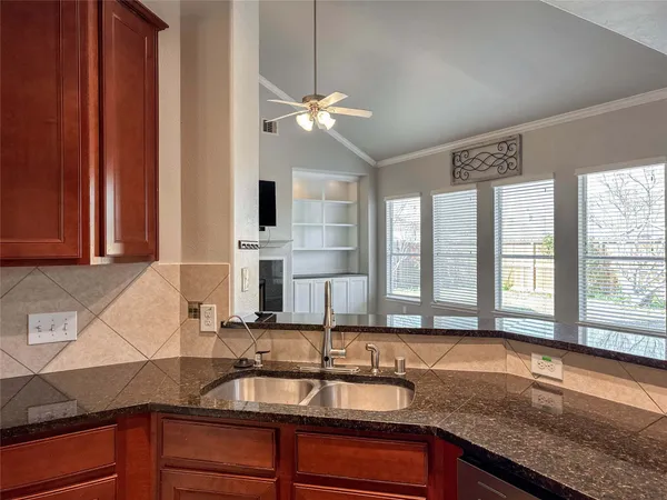 a kitchen with granite countertop a sink a counter top space and cabinets