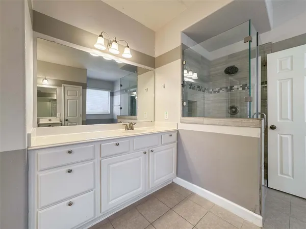 a spacious bathroom with a shower a sink and a mirror
