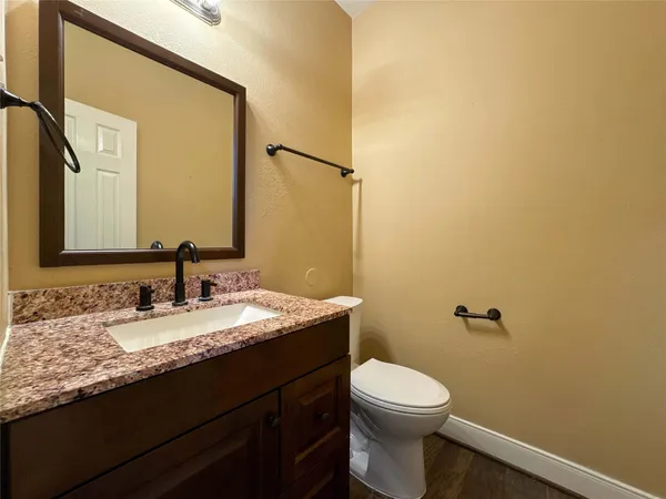 a bathroom with a granite countertop toilet sink and mirror