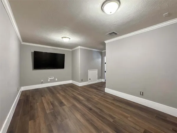 a view of an empty room with wooden floor and windows