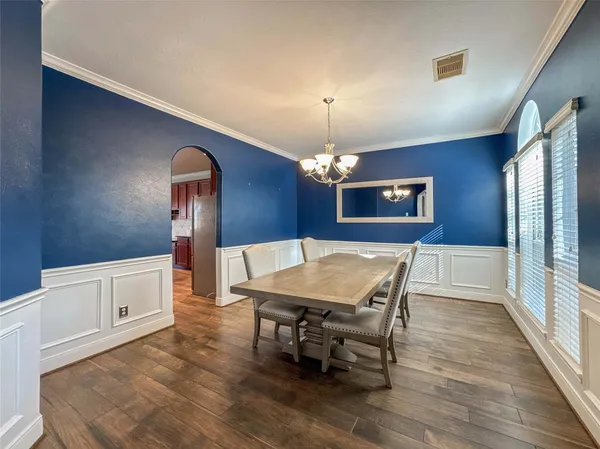 a dining room with wooden floor a chandelier a wooden table and chairs