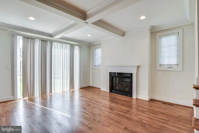 an empty room with wooden floor fireplace and windows