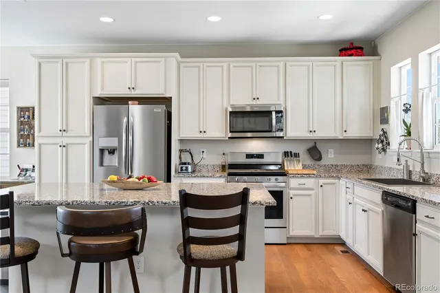 a kitchen with stainless steel appliances a stove a sink dishwasher a refrigerator and cabinets with wooden floor