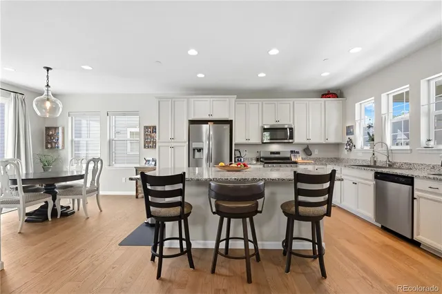 a kitchen with stainless steel appliances granite countertop a stove a refrigerator a kitchen island with chairs and wooden floor