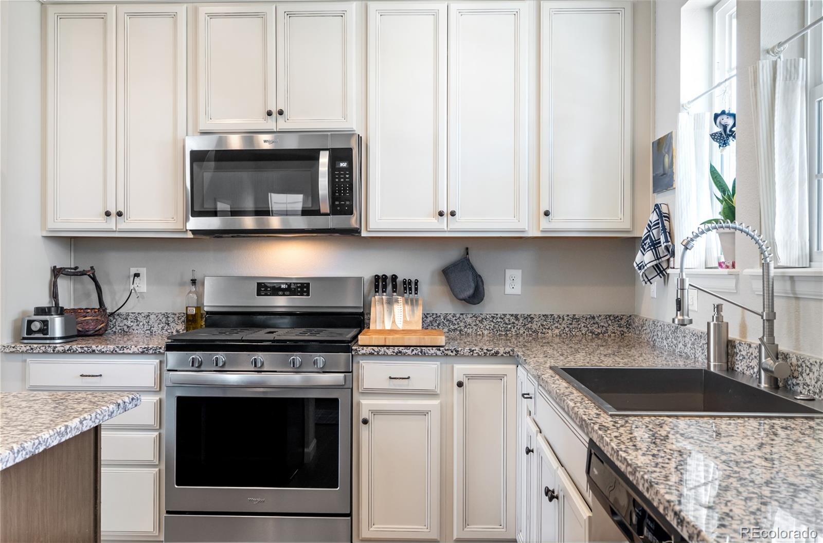 10074 Flower Street Broomfield, CO 80021 - Photo 14 of 47 a kitchen with stainless steel appliances granite countertop a stove a sink and a white cabinets