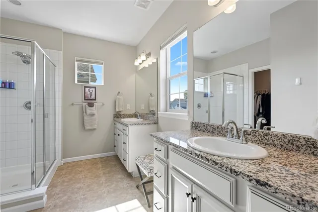 a bathroom with a granite countertop sink a mirror and a shower