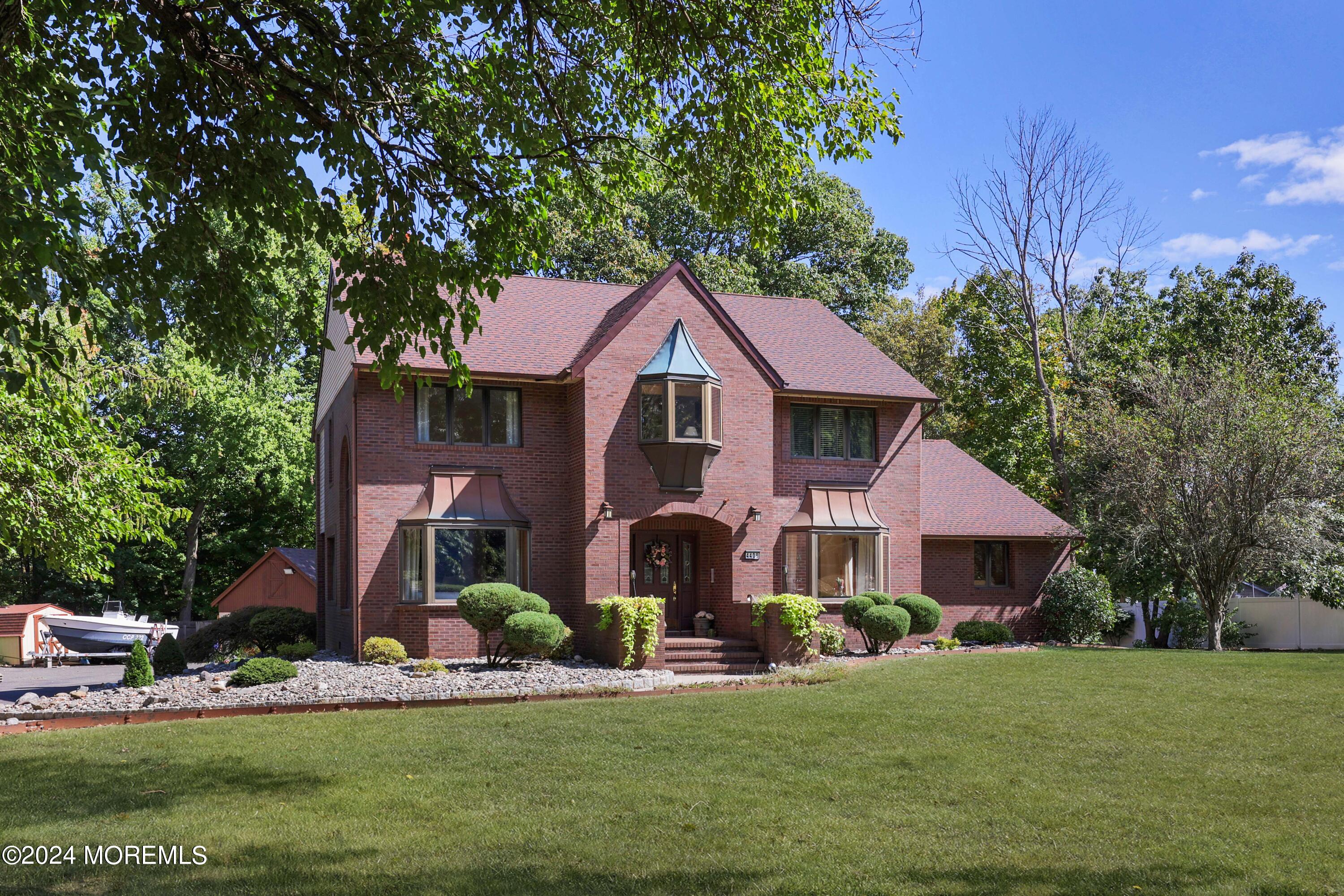 a front view of a house with a garden and trees