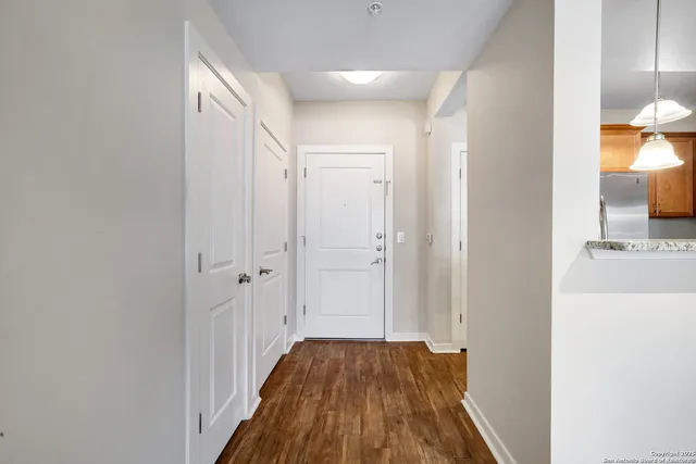 a view of a hallway with wooden floor and a bathroom