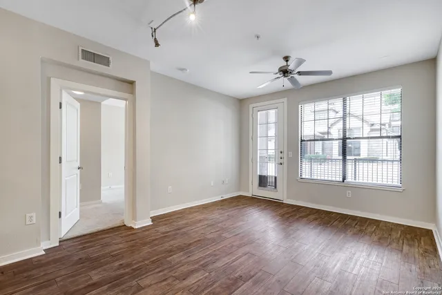 a view of an empty room with wooden floor and a window