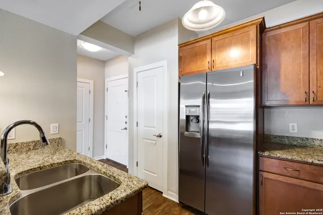 a kitchen with granite countertop a refrigerator and a sink