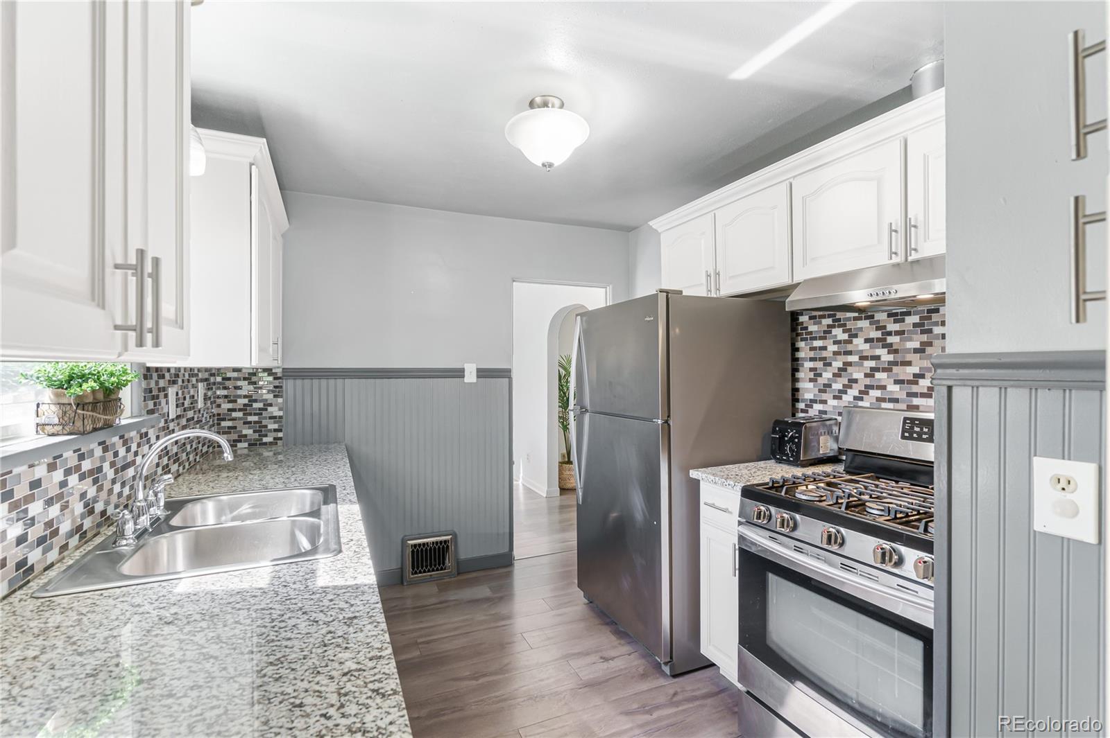 3880 Reed Street Wheat Ridge, CO 80033 - Photo 16 of 40 a kitchen with granite countertop a refrigerator stove and sink