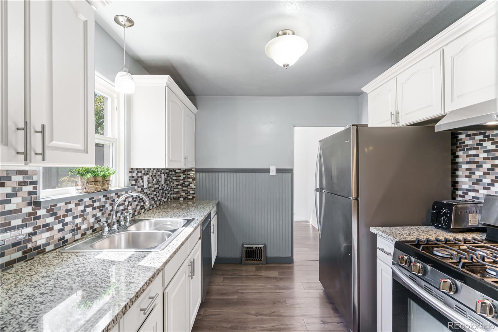 3880 Reed Street Wheat Ridge, CO 80033 - Photo 17 of 40 a kitchen with granite countertop a sink stove and refrigerator