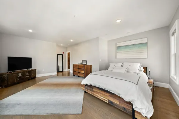 a spacious bedroom with a bed and a flat screen television