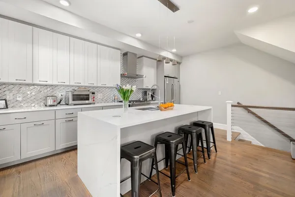a kitchen with stainless steel appliances kitchen island a table chairs sink and cabinets