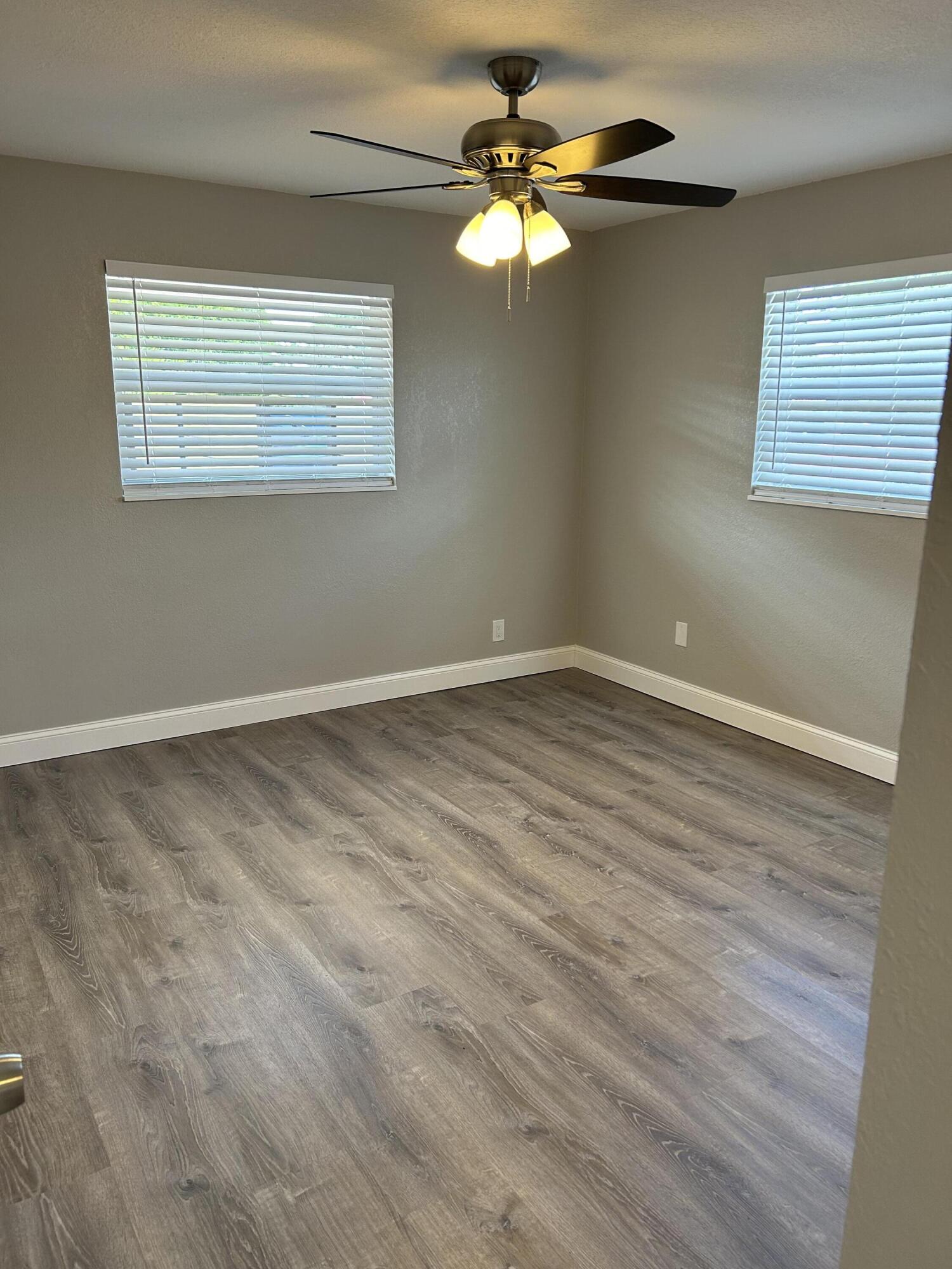 628 North M Street, Unit 1 Lake Worth Beach, FL 33460 - Photo 11 of 11 an empty room with wooden floor chandelier fan and windows
