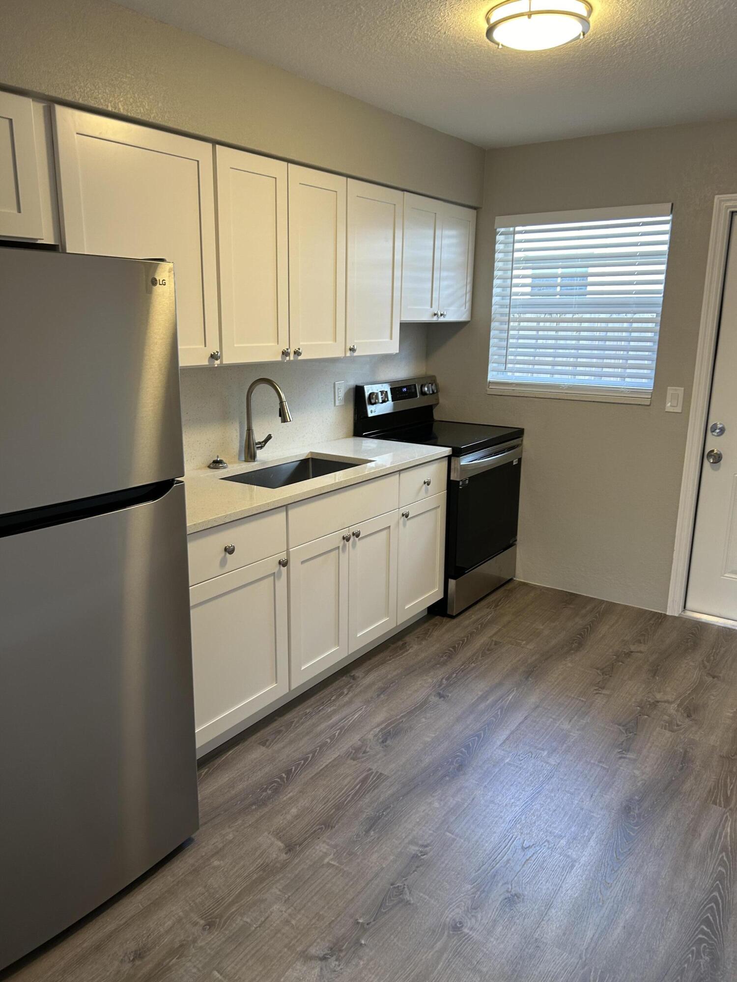628 North M Street, Unit 1 Lake Worth Beach, FL 33460 - Photo 7 of 11 a kitchen with stainless steel appliances granite countertop a refrigerator sink and white cabinets