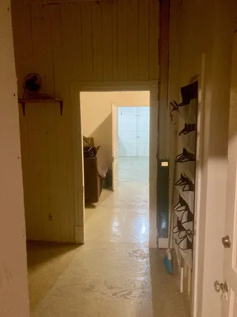 a view of a hallway with wooden floor and a bathroom