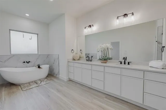 a bathroom with a double vanity sink mirror and bathtub