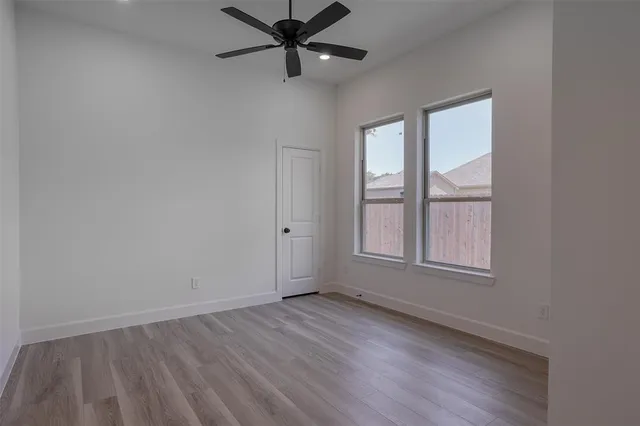 an empty room with wooden floor closet and windows