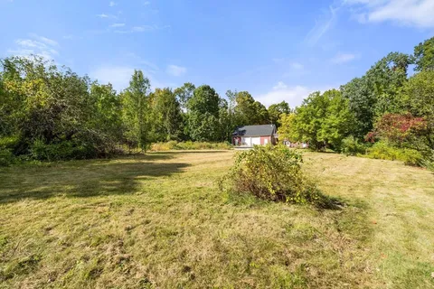 an aerial view of a house with a yard and trees all around