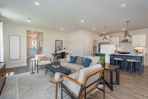 a living room with a dining table wooden floor and kitchen view