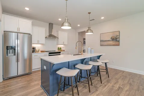 a kitchen with stainless steel appliances a dining table chairs and wooden floor